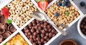 Variety of cold quick breakfast cereals with berries in white wooden box and other ingredients for breakfast, healthy eating concept, top view.