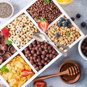 Variety of cold quick breakfast cereals with berries in white wooden box and other ingredients for breakfast, healthy eating concept, top view.